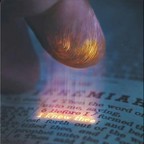 A fingertip glowing above an open Bible, illuminating a single line of text