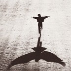 A young person running with arms outstretched, casting the shadow of a great bird